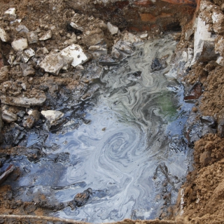 Stark belastetes Stauwasser mit Ölteppich